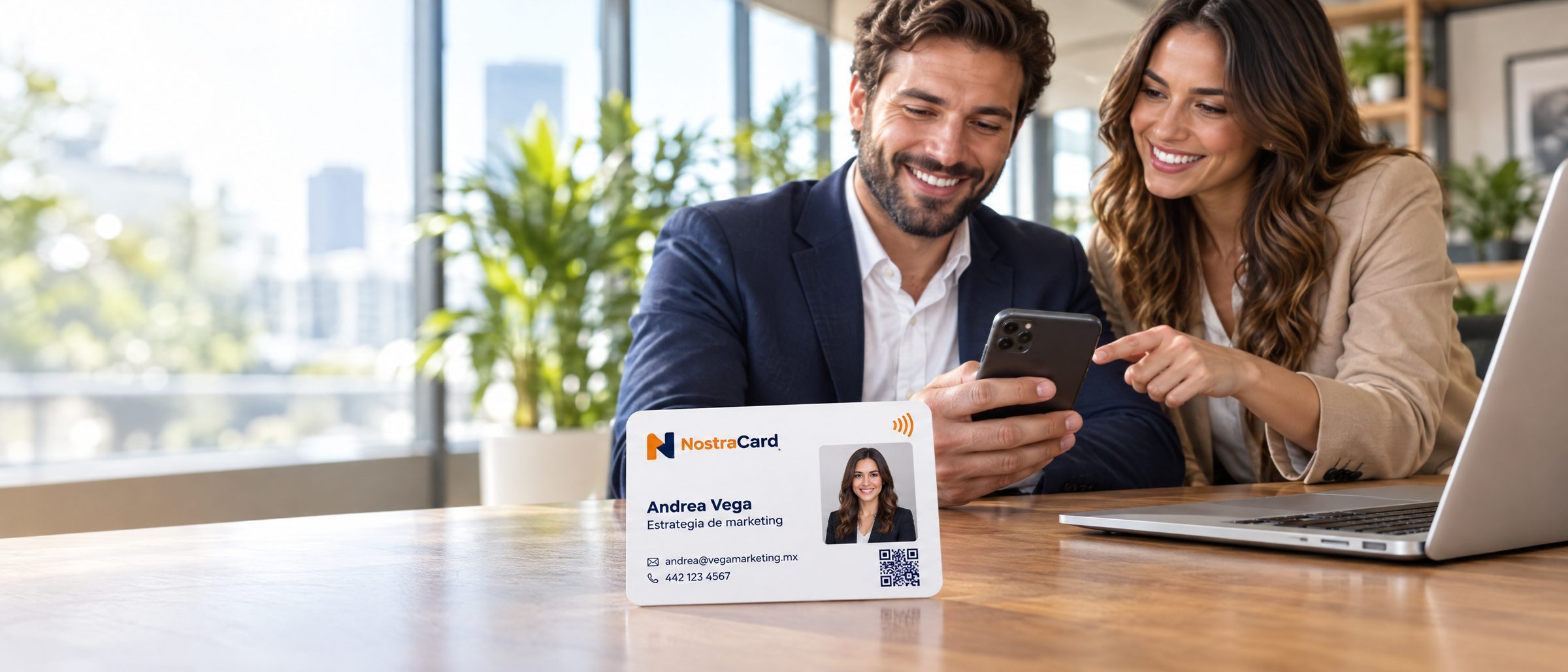 Dos profesionales revisan un perfil digital en un teléfono, con una tarjeta NostraCard de Andrea Vega sobre la mesa.